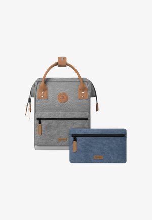 Grau gestreifter Stoffrucksack mit einem braunen Ledergriff und Akzenten, ausgestattet mit einer vorderen Reißverschlusstasche und einem blauen Beutel daneben.