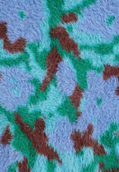 Gros plan d'un tissu duveteux avec un motif floral abstrait en bleu, vert et marron.