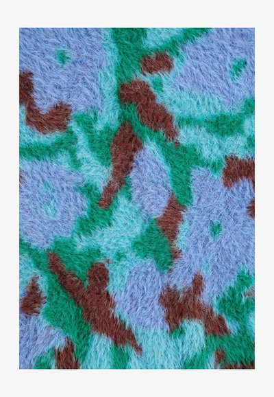 Gros plan d'un tissu duveteux avec un motif floral abstrait en bleu, vert et marron.