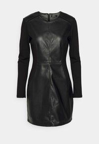 Svart klänning med en läderkropp och en slät yta, långa svarta ärmar och en figursydd silhuett. Dragkedja bak.