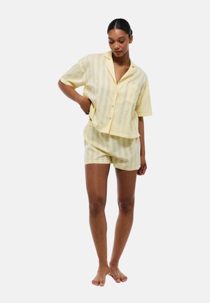 Chemise à manches courtes rayée jaune avec une poche et un short assorti, fabriqués en tissu léger, présentant un design décontracté.