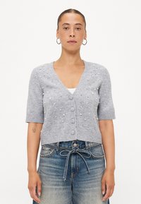 Grijze gebreide cardigan met een v-hals, korte mouwen en knopen. Bevat versieringen van parels en kralen over de voorkant.