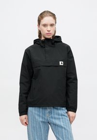 Μαύρο pullover σακάκι από ελαφρύ υλικό, με κουκούλα, μπροστινό φερμουάρ και λογότυπο στο στήθος. Συνδυασμένο με ανοιχτόχρωμο ριγέ τζιν.
