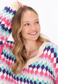 Kolorowy sweter robiony na drutach z grubym, teksturowanym wzorem w kolorach różowym, fioletowym, miętowym i kremowym. Szeroki dekolt i ściągacze.