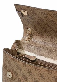 Sac à main marron à motif avec quincaillerie en or poli. L'intérieur comprend une poche zippée et une doublure en tissu. Fermeture à rabat avec bouton-pression.