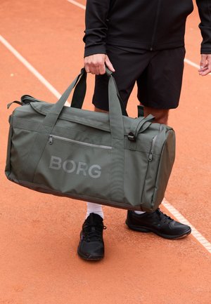 Green duffel bag with "BORG" logo, made from durable fabric, featuring multiple handles, a zippered front pocket, and a structured shape.