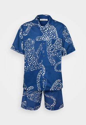 Chemise en coton bleue à manches courtes et shorts assortis avec un motif léopard blanc. La chemise a un boutonnage sur le devant et une poche.