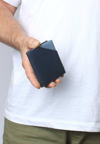 Marine leren portemonnee met een slank ontwerp, voorzien van een lichtblauwe accenten, afgeronde hoeken en een reliëf merknaam aan de voorkant.