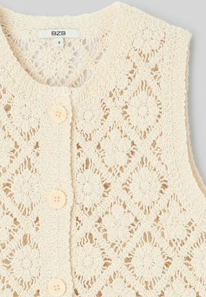 Veste en tricot crochet couleur crème avec motifs floraux et losanges, col rond et trois boutons crème sur le devant.