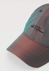 Baseballcap mit einem Farbverlauf von Dunkelrot nach Türkis, aus glattem Stoff, mit einem gestickten Logo und auffälligen Nahtdetails.