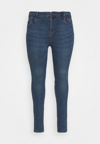 Jeans ajustados en denim azul oscuro con una textura suave, cinco bolsillos y cierre de cremallera. Presenta un desgaste sutil a lo largo de los muslos.