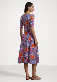 Abito floreale con corpetto aderente, gonna ampia, maniche corte, di colore blu con fiori arancioni e rossi. Tessuto morbido e design a lunghezza ginocchio.
