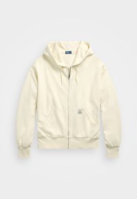 Jasnokremowa bluza z kapturem na zamek, wykonana z miękkiego materiału, z przednią kieszenią, sznurkami przy kapturze oraz małą naszywką z logo.