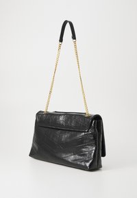 Black quilted leather handbag with a structured design, gold chain strap, and a fold-over flap featuring chevron detailing.
