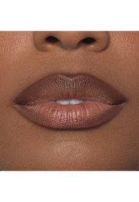 Braune matte Lippenfarbe auf glatten Lippen, die einen subtilen Glanz, klar definierte Lippenkonturen und einen natürlichen Hautton im Hintergrund zeigt.
