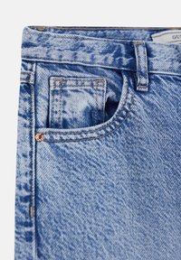 Jeans en denim bleu clair avec une texture délavée, dotés d'une poche frontale, de quincaillerie de couleur cuivrée et de coutures classiques.