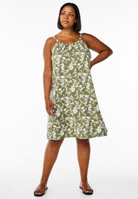 Olivno zelena obleka z belim cvetličnim vzorcem, oprijetim zgornjim delom in nastavljivimi naramnicami; sproščenega A-oblika, dolžine do kolen, iz lahkega blaga.