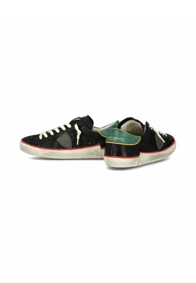 Sorte ruskind sneakers med hvide snørebånd og gummisåler. Har grøn accent på hælen og rød stribe langs sålen. Rent design.