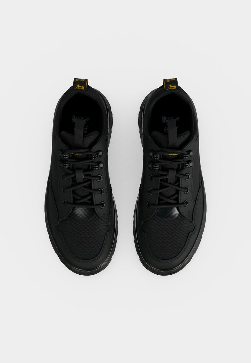 Paar schwarze Schnürsneaker mit dicken Sohlen, von oben auf weißem Hintergrund gesehen.