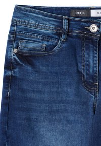 Jean en denim bleu foncé avec une texture lisse, des coutures visibles, une poche avant et une étiquette logo sur la ceinture.