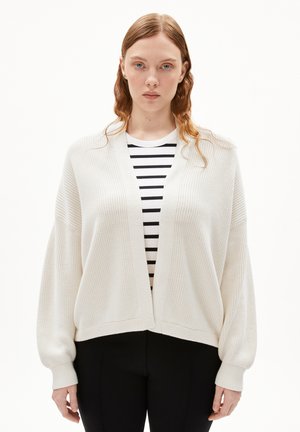 Cardigan leggero e texturizzato con spalle scese e scollatura a V, abbinato a un top a righe bianche e nere sotto.