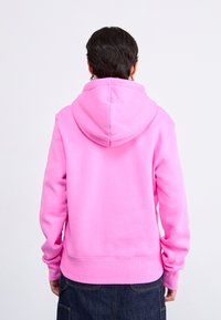 Roze hoodie met een trekkoord in de capuchon en ribgebreide manchetten en zoom. Zachte stof met een gladde textuur. Zicht van achteren, met een minimaal ontwerp.