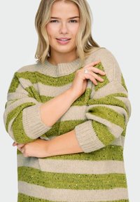 Beige trui met groene strepen, geribbelde boorden en een ronde halslijn. De stof lijkt textuur te hebben met een losse brei. Is versierd met subtiele pailletten.