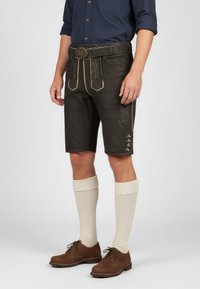Brown leather shorts with decorative stitching, a wide belt with a metal buckle, paired with knee-high textured cream socks and brown shoes.