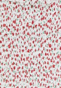 White fabric with a smocked texture, featuring a floral pattern of red flowers and green leaves, densely arranged across the surface.