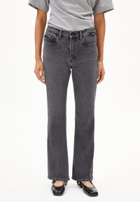 Zwarte denim jeans met een rechte snit, medium hoge taille, vijfzakkenontwerp en subtiele vervaging. Gemaakt met een grijs t-shirt en zwarte ballerina's.