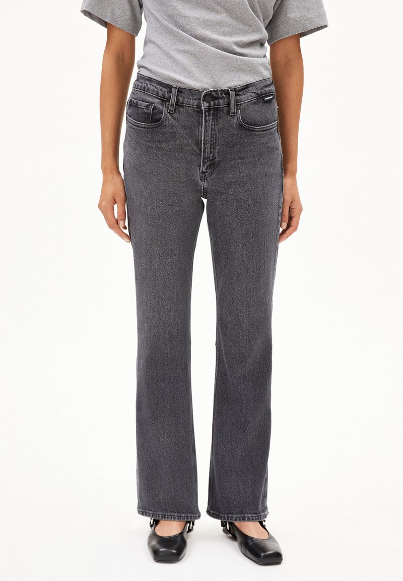 Zwarte denim jeans met een rechte snit, medium hoge taille, vijfzakkenontwerp en subtiele vervaging. Gemaakt met een grijs t-shirt en zwarte ballerina's.