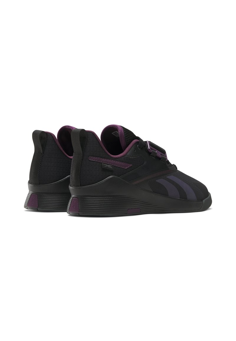 Czarne buty sportowe z purpurowymi akcentami, z teksturowaną cholewką, mocnym paskiem oraz solidną konstrukcją podeszwy.