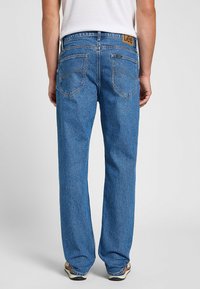 Jeans de mezclilla azul con un corte relajado, que presentan una pierna recta, costuras amarillas y una etiqueta de cuero con el logo de Lee en la parte trasera de la cinturilla.