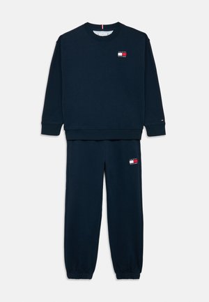 Komplet granatowej bluzy i spodni dresowych z logo Tommy Hilfiger na piersi i udzie, ze ściągaczami na rękawach i elastycznymi zakończeniami nogawek.