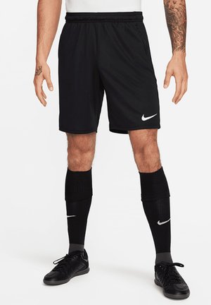 Black Nike athletic shorts with an elastic waistband, moisture-wicking fabric, and a white Nike logo on the lower left front. Black socks and shoes.