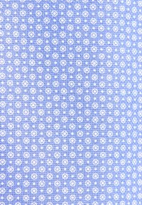 Tissu bleu avec un motif répétitif de cercles blancs et de points, tissage texturé visible.