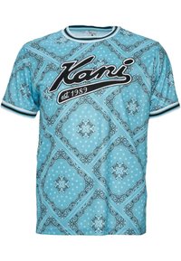 Camisa de manga corta azul claro con patrones de paisley en blanco y negro, cuello y puños a rayas, y el logo "Kani est. 1989" en el pecho.
