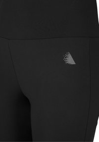 Czarne legginsy wykonane z gładkiego, elastycznego materiału, z małym, teksturowanym srebrnym logo z boku oraz dopasowanym, smukłym krojem.