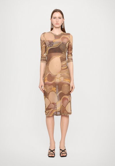 Rochie transparentă maro cu modele abstracte în bej și tonuri mai închise. Mâneci lungi, de lungime medie, asortată cu sandale negre cu barete.