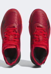 Zapatillas deportivas rojas con una parte superior de malla texturizada, cordones y detalles en negro. Cuentan con una suela acolchada y un diseño elegante y aerodinámico.