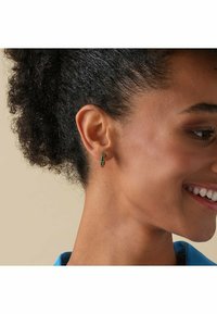 Smaragdgröna hoopsörhängen med en texturerad yta, med en liten diameter, visade mot en neutral bakgrund.