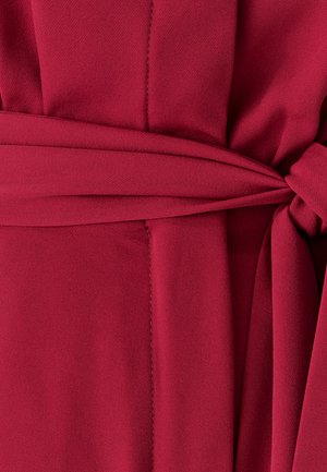 Red fabric with a smooth texture, featuring a tied belt detail and clean stitching along the edges.
