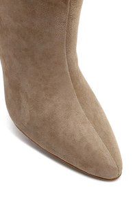Stivaletto in suede beige con punta affusolata e texture liscia. Il tacco è slanciato e presenta un design senza cuciture, senza elementi hardware visibili.