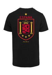 Fekete póló, amelyen egy piros és sárga spanyol címer látványos dizájnja található az "ESPAÑA" és "2024" felirattal, az alján pedig a "¡A por ellos, oe!" szöveggel.