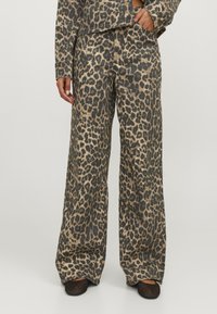 Wide-leg pants featuring a leopard print pattern in shades of beige and black. Made from a smooth material with a loose fit.