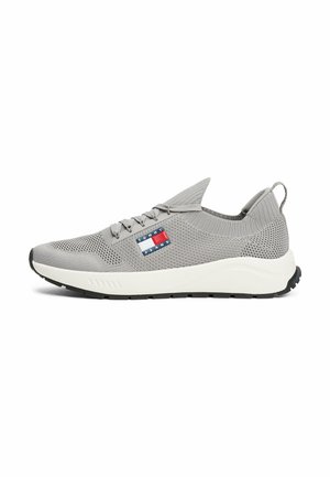 Grauer Sportschuh mit einem Obermaterial aus Mesh, weißer Mittelsohle und schwarzer Außensohle. Verfügt über ein Logo-Patch mit roten, weißen und blauen Elementen.