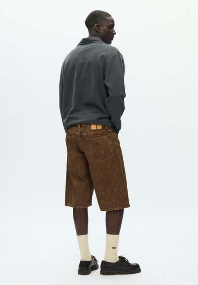 Brown denim shorts with a marbled texture, paired with a dark gray long-sleeve shirt, cream socks, and black shoes.