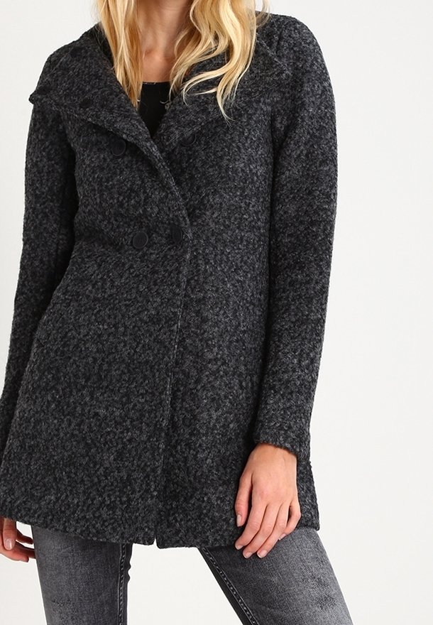 Femme portant un manteau en laine texturée gris foncé à boutons croisés et col large, associé à un jean gris.