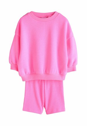 Jasnoróżowa dzianinowa bluza z długim rękawem i dopasowane prążkowane szorty, prezentowane na białym tle.