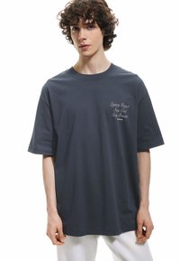Camiseta de algodón azul marino de mangas cortas, con texto bordado en blanco en el pecho. Diseño de cuello redondo y corte relajado.